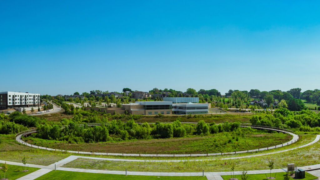 Round circular bridge in the distance on a green landscape under a blue sky.